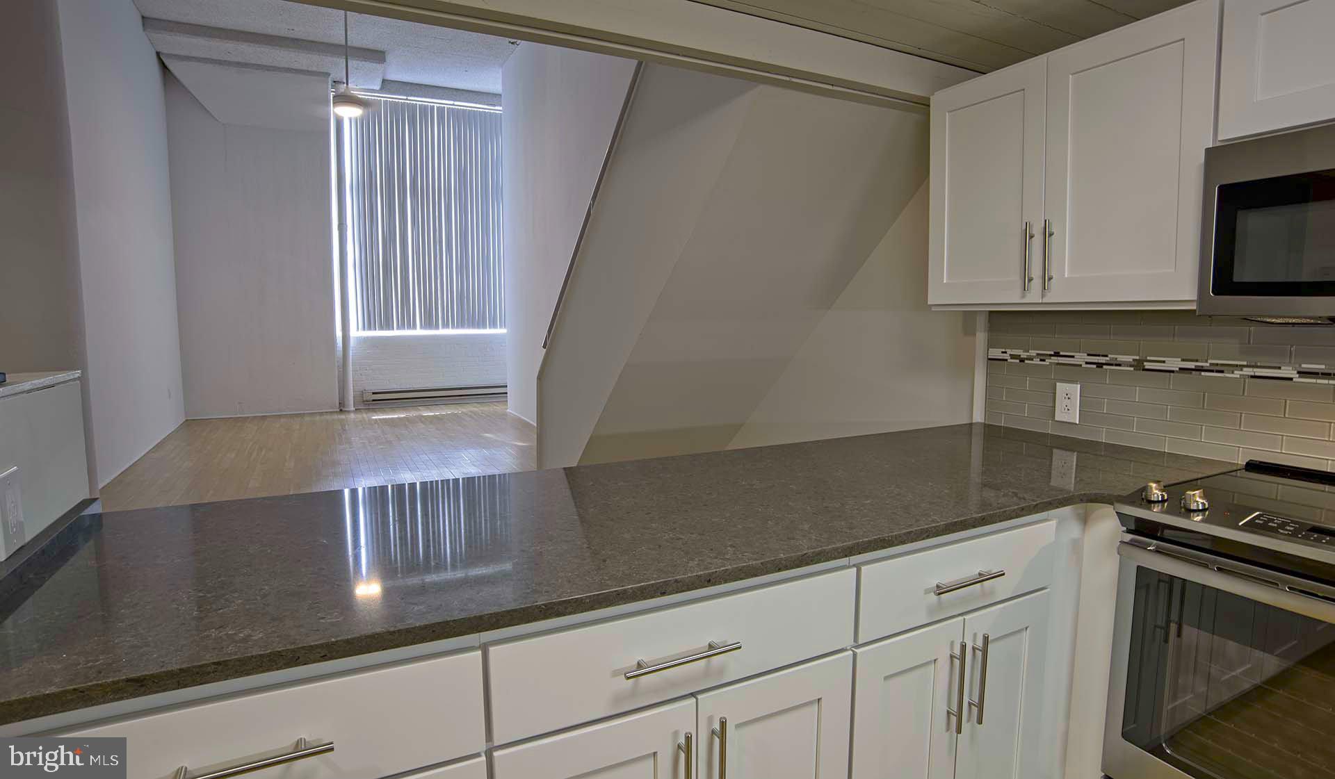 2300 Walnut Street, Unit 1B717 Philadelphia, PA 19103 - Photo 16 of 27 a kitchen with granite countertop white cabinets and black appliances
