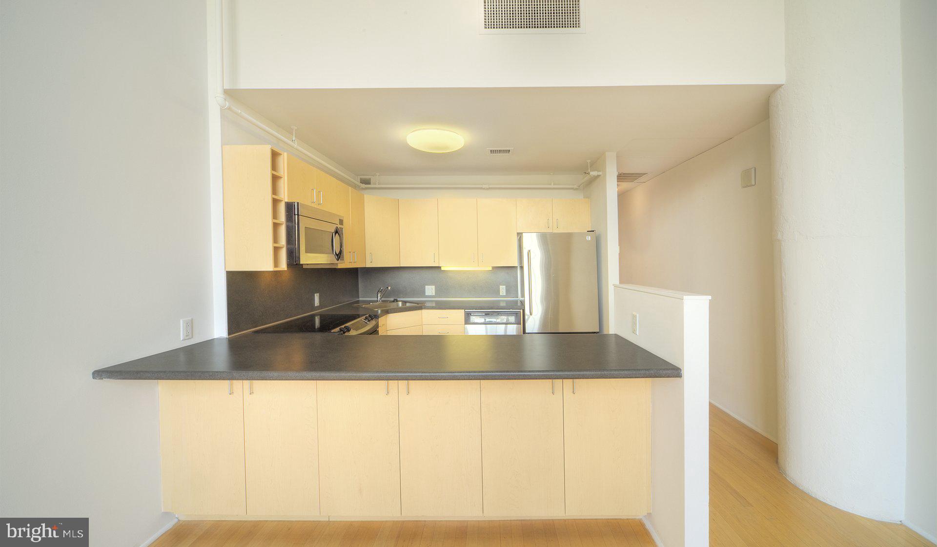 2300 Walnut Street, Unit 1B717 Philadelphia, PA 19103 - Photo 22 of 27 a view of a kitchen with kitchen island a sink wooden floor and a large window