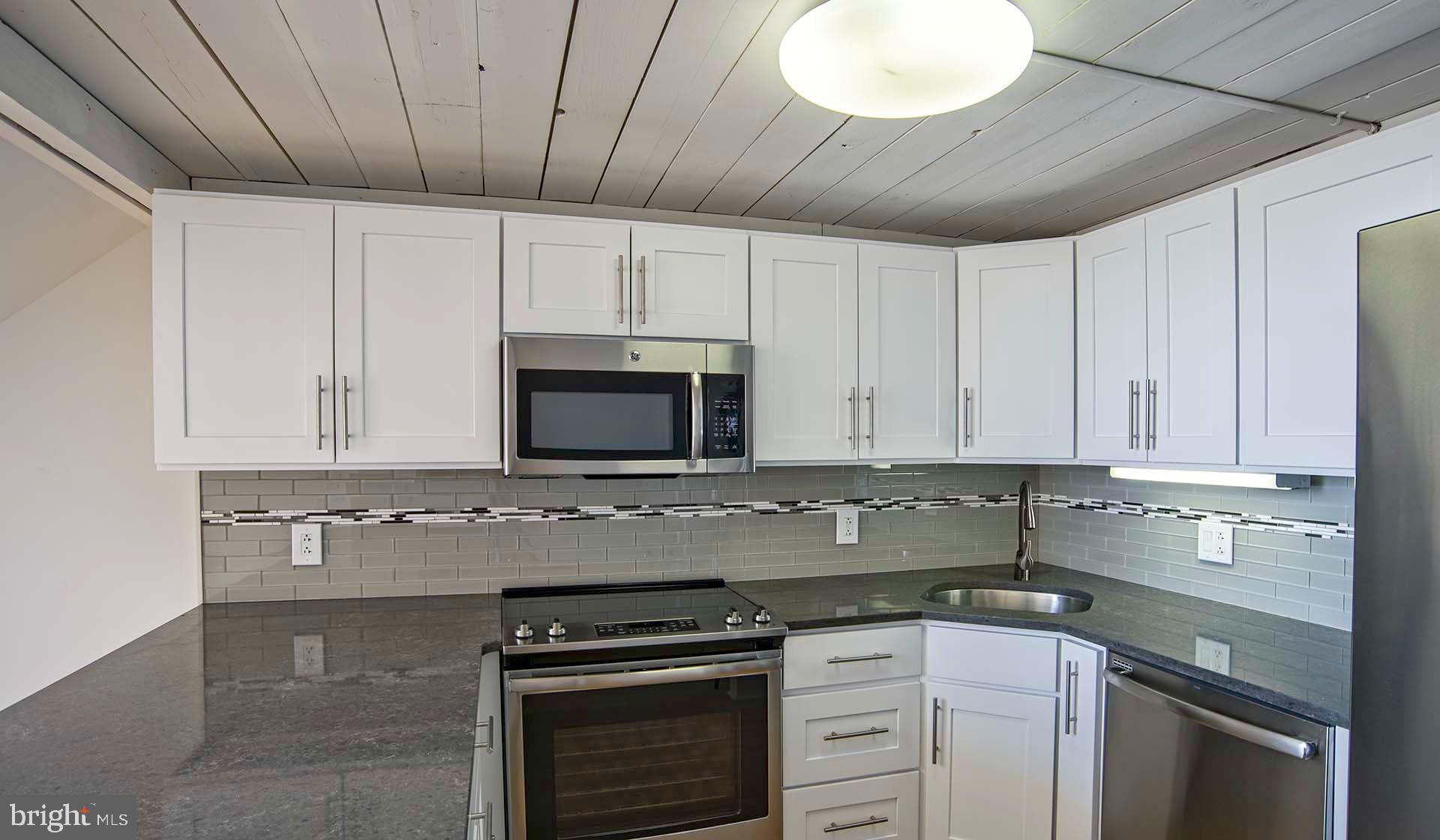 2300 Walnut Street, Unit 1B717 Philadelphia, PA 19103 - Photo 23 of 27 a kitchen with stainless steel appliances granite countertop a stove a sink and a microwave