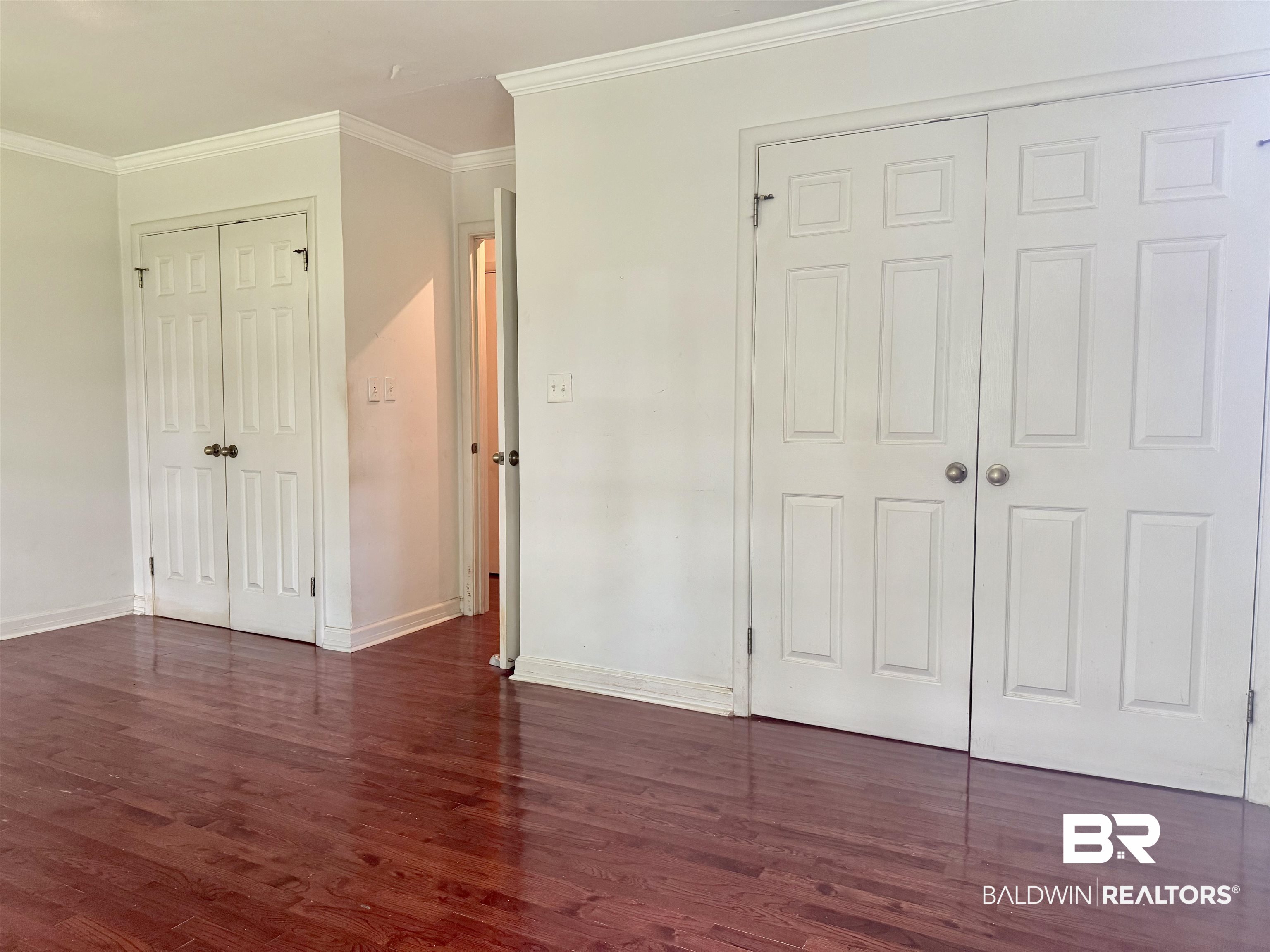 1412 Poplar Avenue Brewton, AL 36426 - Photo 21 of 32 Unfurnished bedroom featuring dark wood-type flooring, baseboards, crown molding, and a closet