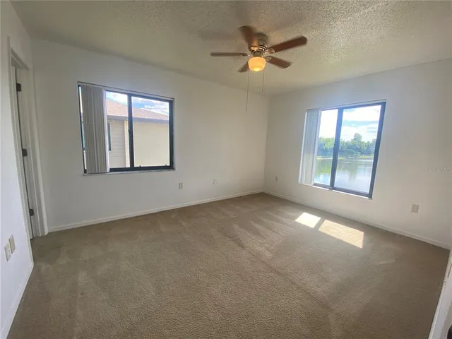 an empty room with windows and ceiling fan