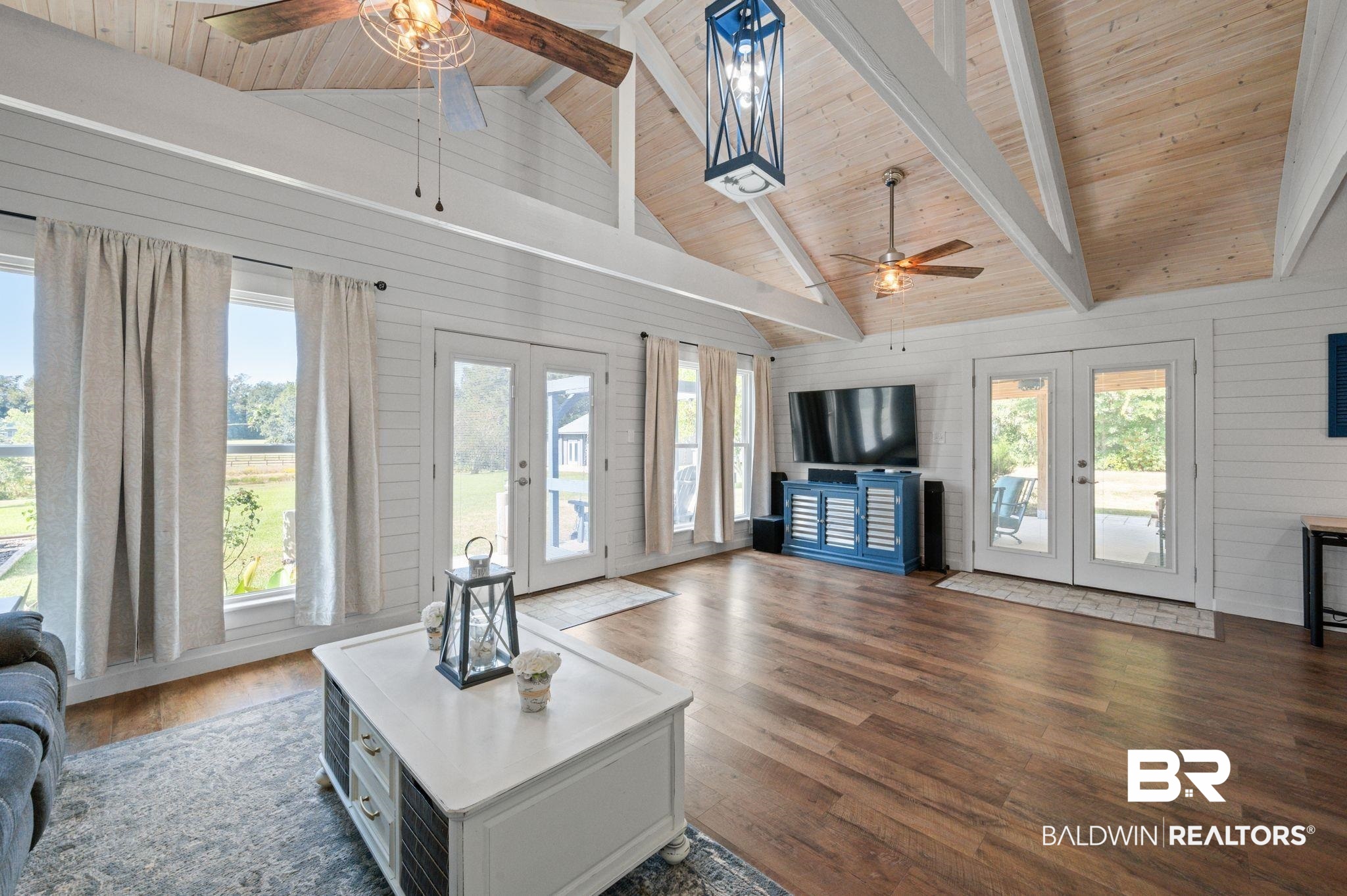 20037 County Road 33 Fairhope, AL 36532 - Photo 12 of 79 Living room with wood ceiling, beam ceiling, wood walls, dark wood-type flooring, and french doors