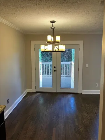 a view of a room with wooden floor chandelier and windows