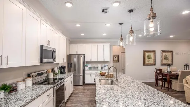 a kitchen with stainless steel appliances granite countertop sink stove refrigerator dining table and chairs