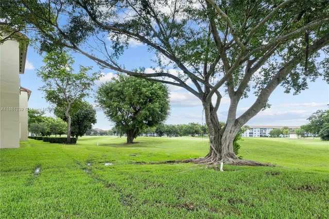 a view of grassy field with benches and trees all around