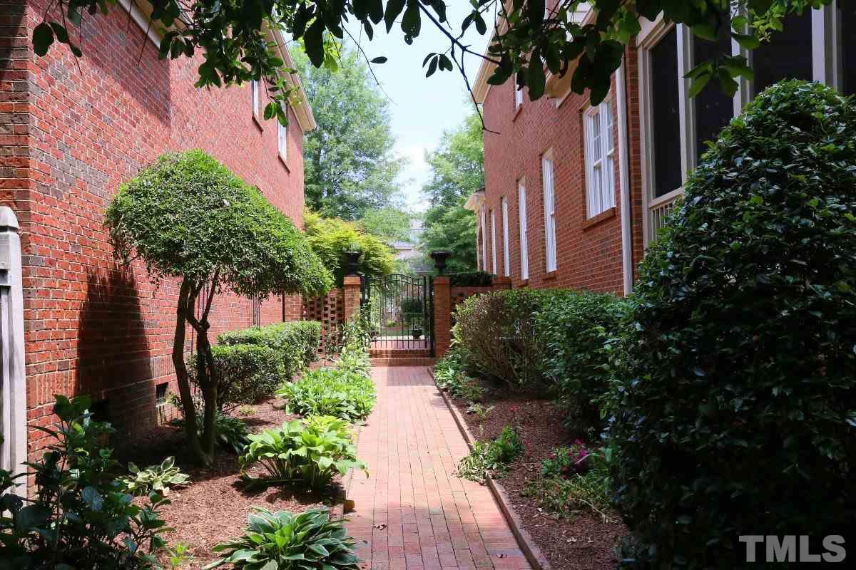 1837 Torrington Street Raleigh, NC 27615 - Photo 21 of 25 Brick path along the side to the wrought iron gate and brick patio beyond