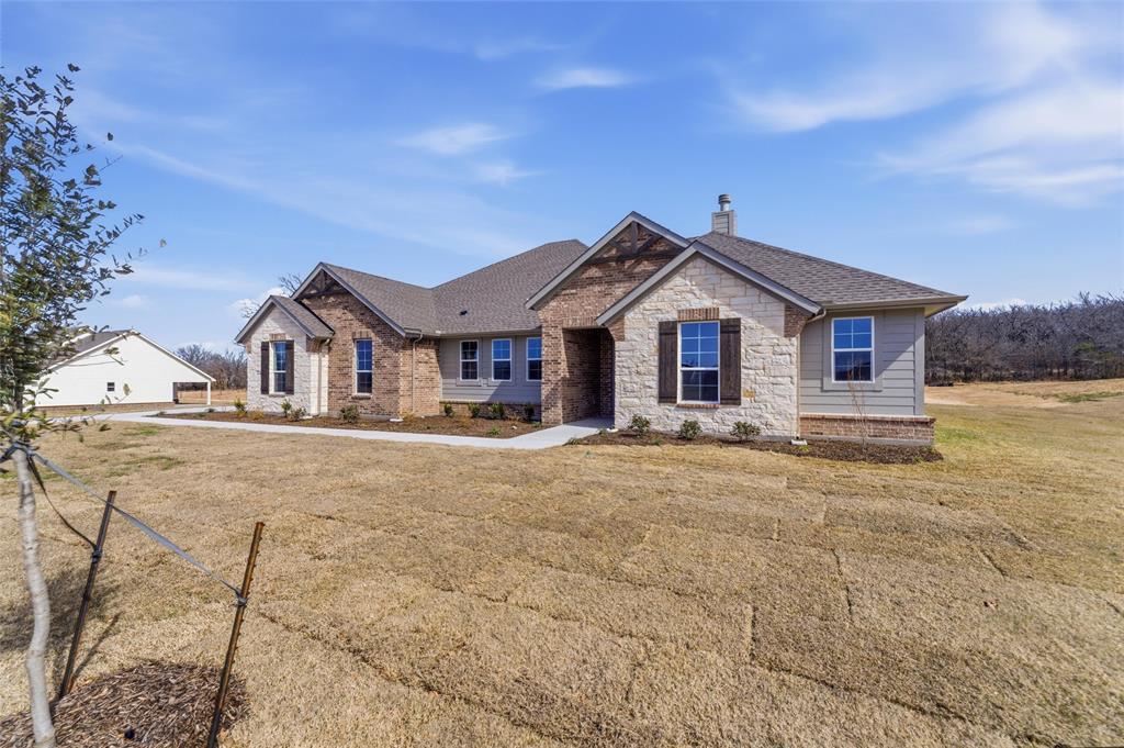 144 Oak Grv Way Springtown, TX 76082 - Photo 4 of 27 a front view of a house with a yard