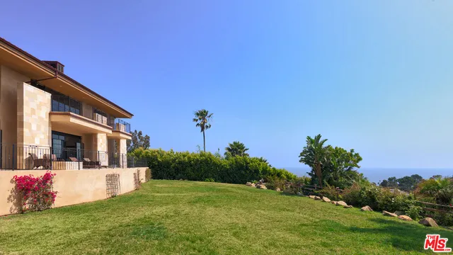 a view of a white house with a big yard and potted plants