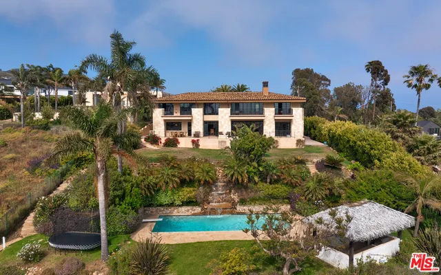 a front view of a house with a yard and fountain in middle