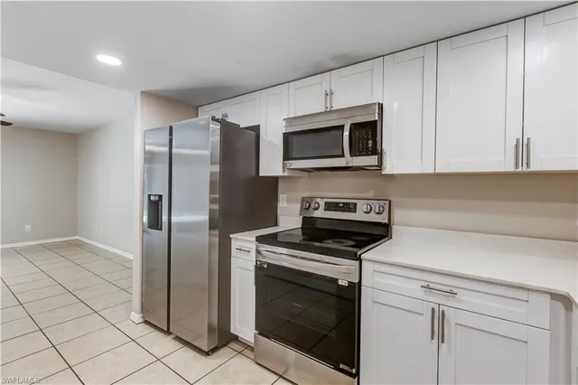 a kitchen with stainless steel appliances granite countertop a refrigerator a stove a microwave oven with white cabinets