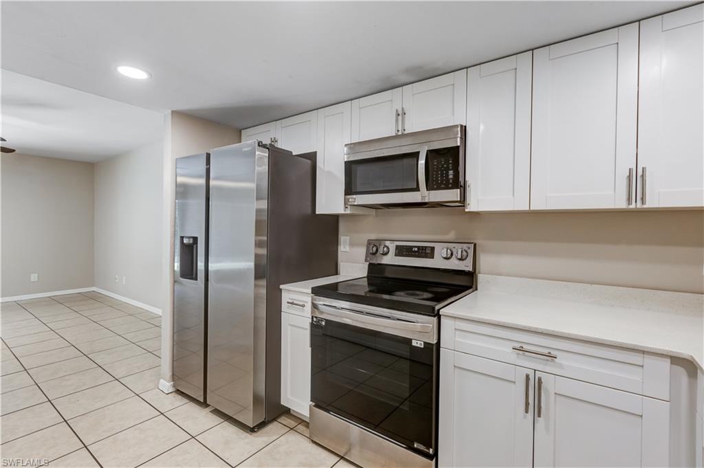 5453 16th Place Southwest Naples, FL 34116 - Photo 3 of 36 a kitchen with stainless steel appliances granite countertop a refrigerator a stove a microwave oven with white cabinets