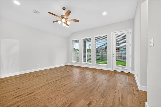 a view of an empty room with wooden floor and a window