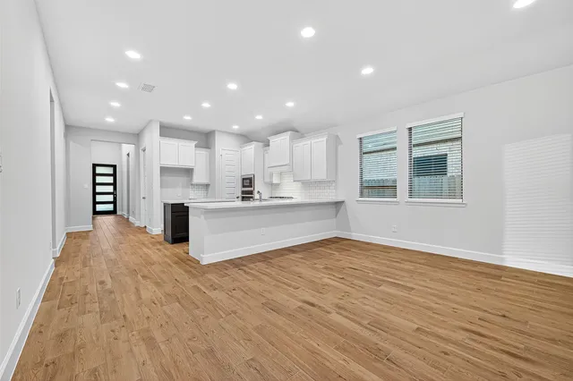 a view of kitchen with kitchen island wooden floor center island and stainless steel appliances