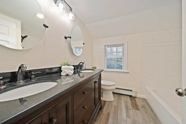a bathroom with a double vanity sink a mirror and a toilet
