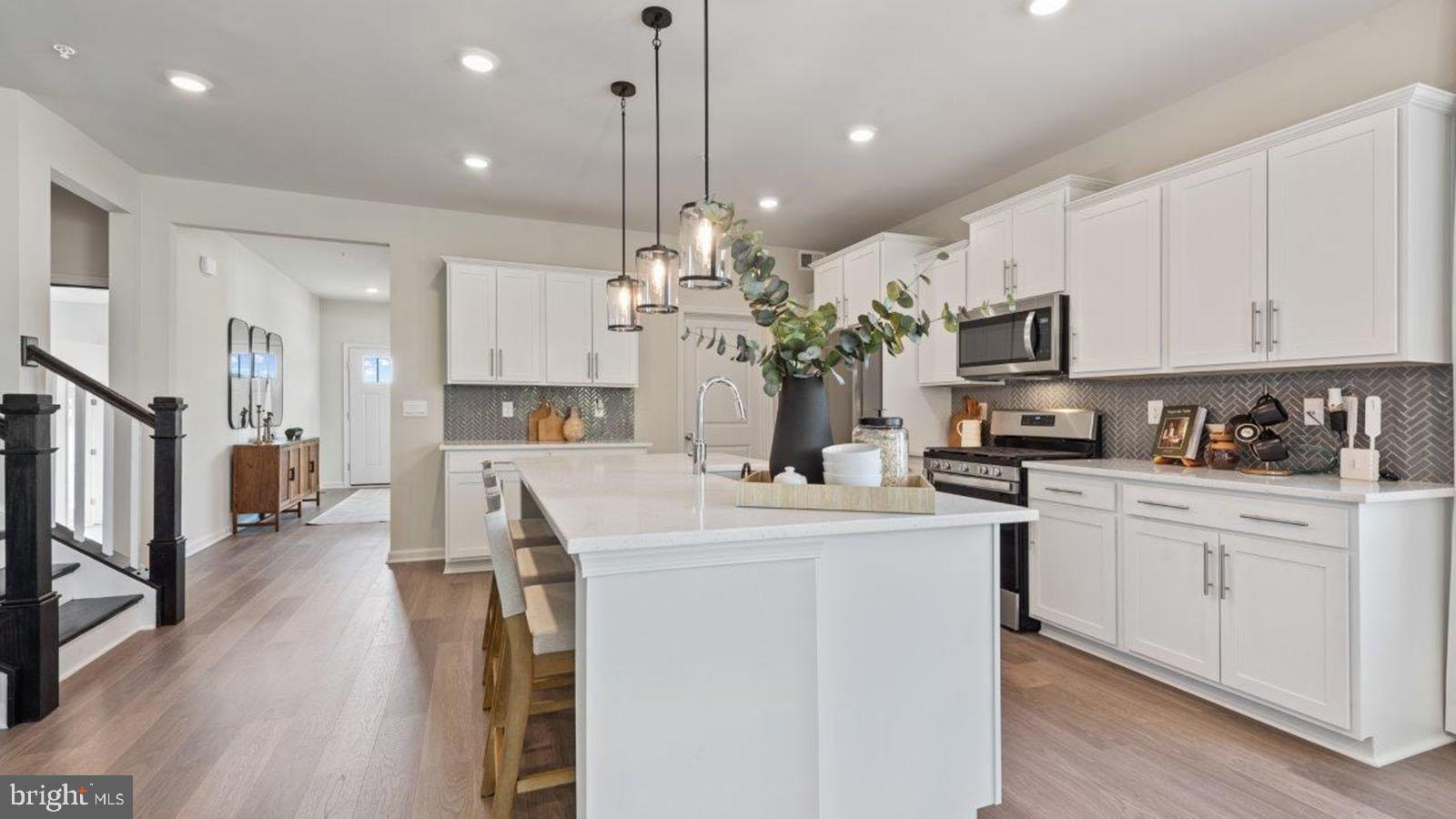 2 Comes Rdg Court Rosedale, MD 21237 - Photo 4 of 29 a kitchen with stainless steel appliances kitchen island a refrigerator a stove a sink dishwasher and a dining table with wooden floor