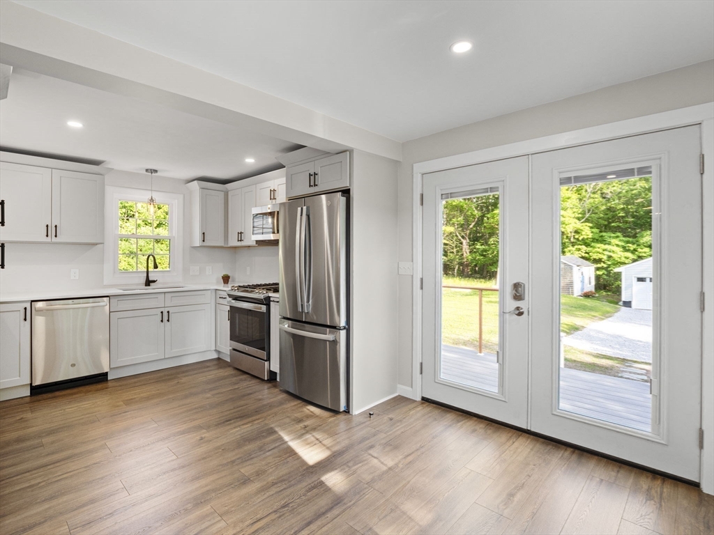 a kitchen with a refrigerator a window and wooden floor