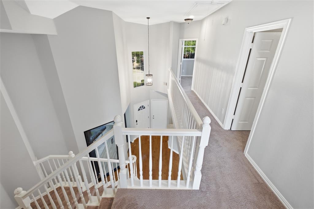 3903 Rive Lane Addison, TX 75001 - Photo 23 of 40 The upstairs landing overlooks the staircase and two-story entry, with a pendant lantern casting a warm glow over the wide carpeted hallway. Bedroom and bath doors line the hall, giving each room its own defined space and privacy.