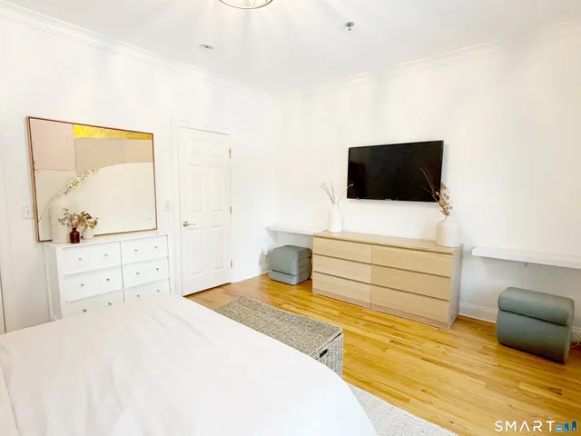 a spacious bedroom with a bed and wooden floor