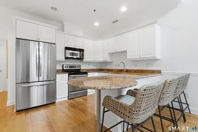 a kitchen with granite countertop a refrigerator stove top oven and sink