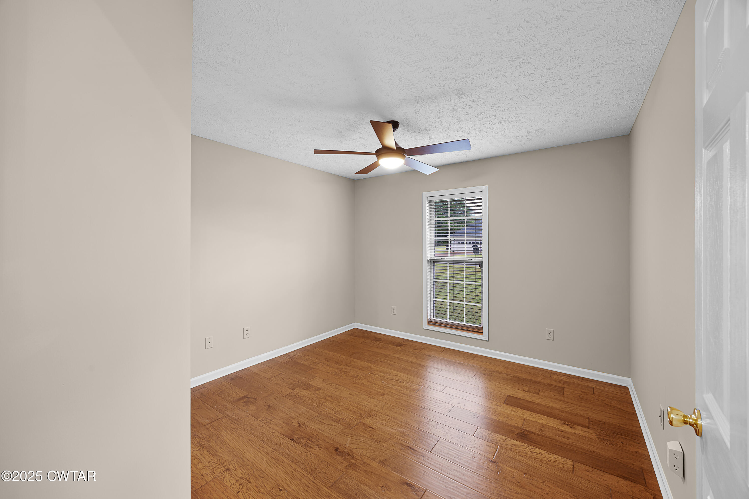 98 Cotton Ridge Drive Jackson, TN 38305 - Photo 13 of 20 an empty room with wooden floor ceiling fan and windows