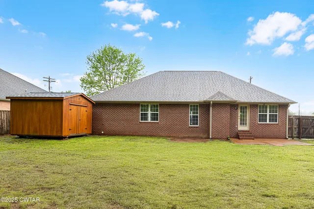 a front view of house with yard and trees in the background