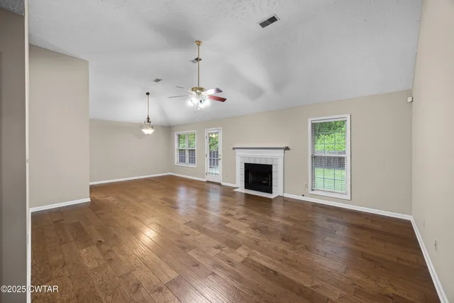 an empty room with wooden floor fireplace and window