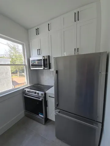 a kitchen with stainless steel appliances a refrigerator a stove a sink and a window