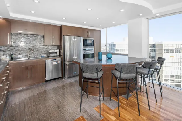 a kitchen with stainless steel appliances kitchen island granite countertop a table chairs stove and refrigerator