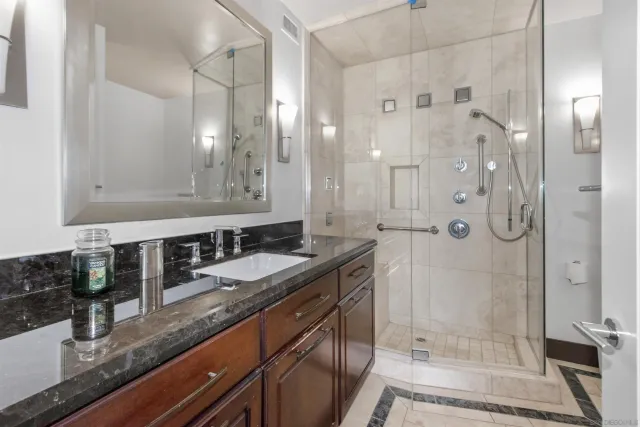 a bathroom with a granite countertop double vanity sink mirror shower and double