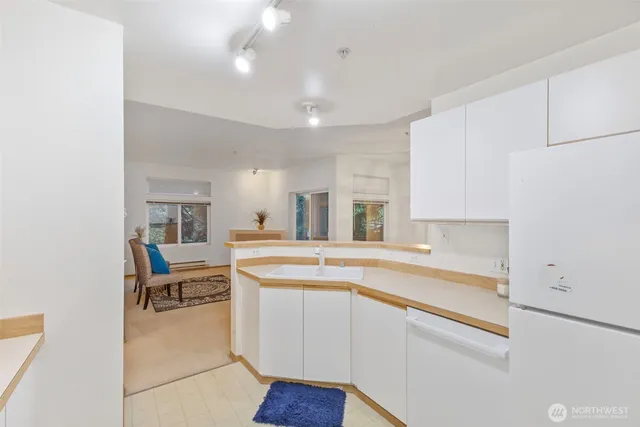 a kitchen with a sink and white cabinets with wooden floors