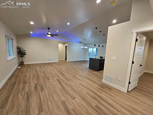a view of a big room with wooden floor and windows