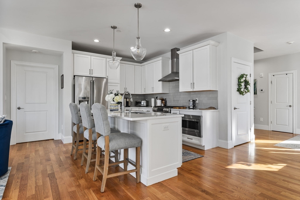 15 Rowell Lane, Unit 15 Middleton, MA 01949 - Photo 11 of 39 a kitchen with stainless steel appliances granite countertop a refrigerator a stove top oven and a center island with wooden floor