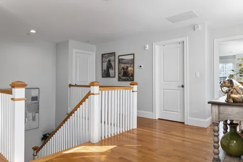 a view of a hallway to a livingroom with wooden floor and stairs