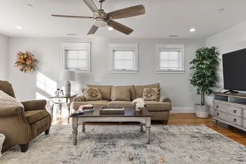 a living room with furniture a flat screen tv and a window