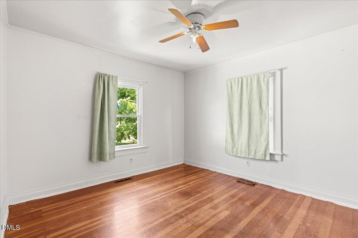 109 Little Ponderosa Road Macon, NC 27551 - Photo 19 of 32 an empty room with wooden floor windows and fan