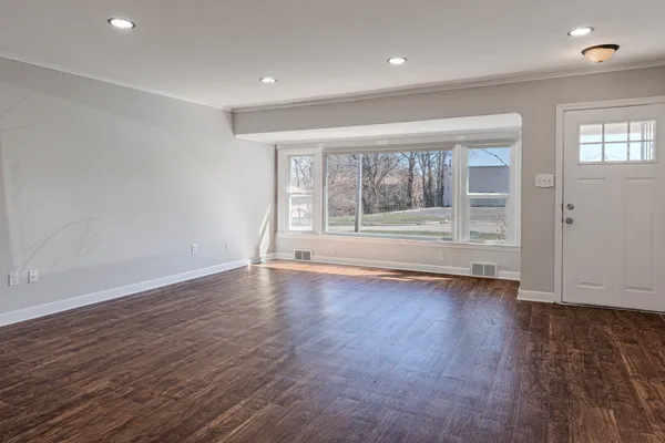 an empty room with wooden floor and windows