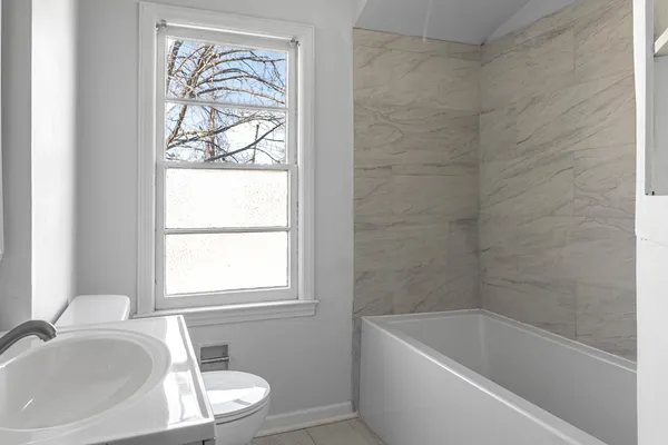 a bathroom with a tub a sink and a window