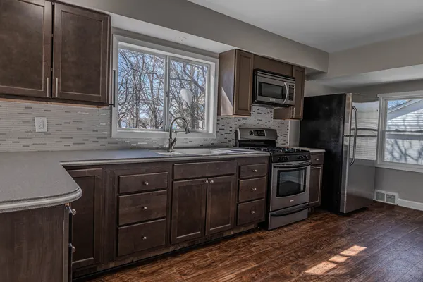 a kitchen with stainless steel appliances granite countertop a stove a sink and a microwave