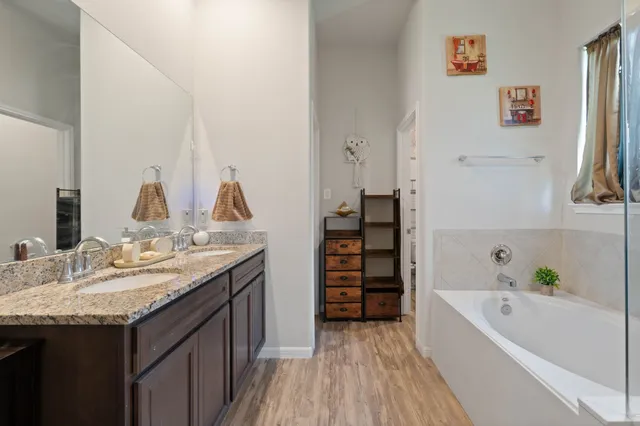 a bathroom with a granite countertop sink a bathtub and a mirror