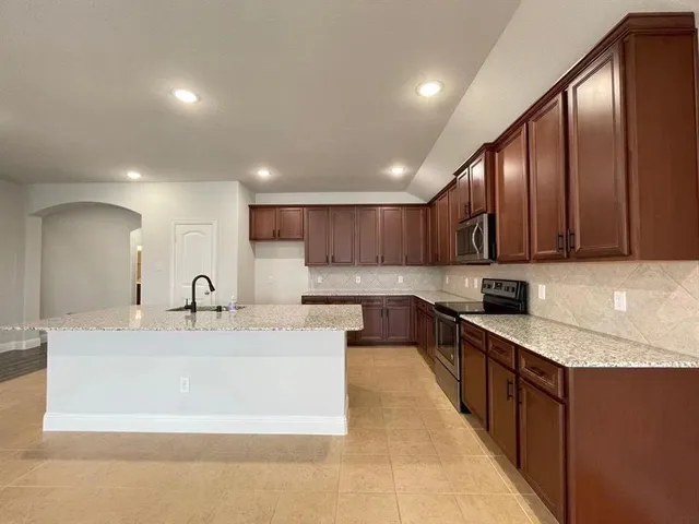 a large kitchen with stainless steel appliances kitchen island a large counter top a sink and a stove