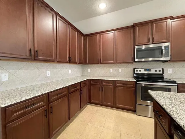 a kitchen with granite countertop wooden cabinets stainless steel appliances and a counter space