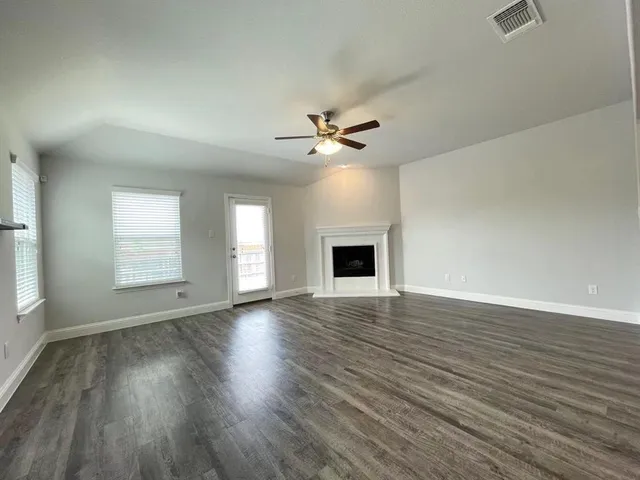 an empty room with wooden floor and chandelier fan