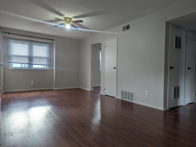 a view of empty room with wooden floor and fan