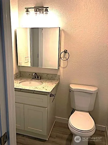 a bathroom with a granite countertop toilet sink and mirror