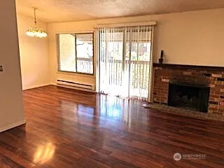 an empty room with wooden floor fireplace and windows
