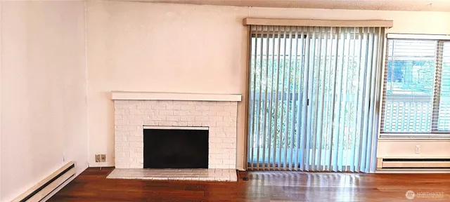 a view of a livingroom with wooden floor and a fireplace