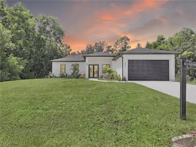 a front view of house with yard and trees in the background