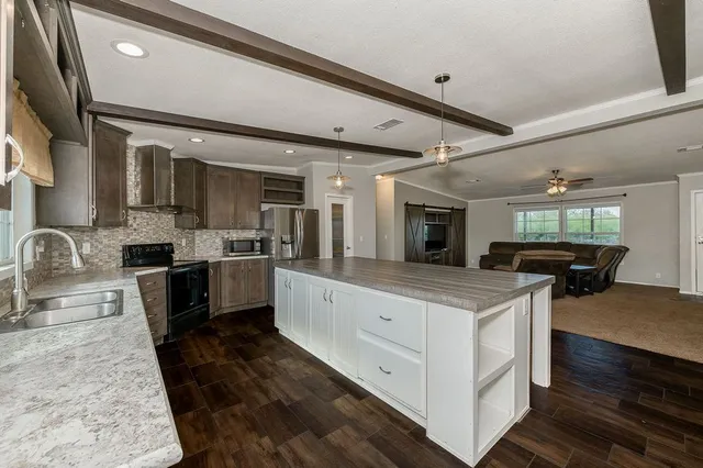 a large kitchen with stainless steel appliances granite countertop a lot of counter space and wooden floor