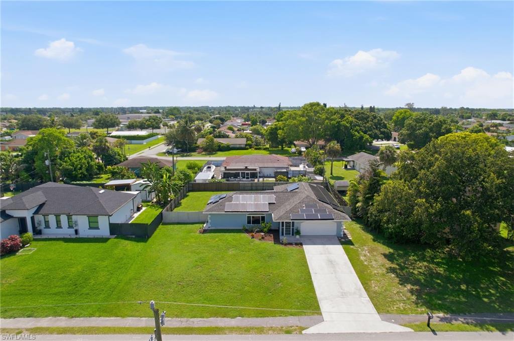 3022 47th Street Southwest Naples, FL 34116 - Photo 41 of 46 Single-story residence featuring a light blue exterior, a dark shingle roof with solar panels, and an attached two-car garage