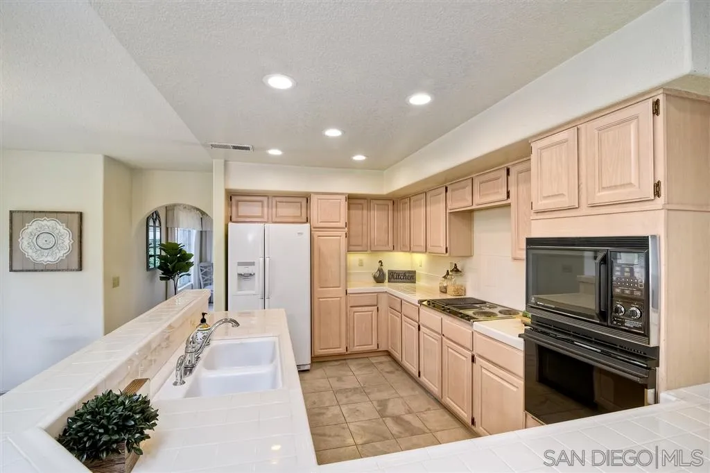 14228 Silver Ridge Road Poway, CA 92064 - Photo 8 of 25 a kitchen with white cabinets and appliances